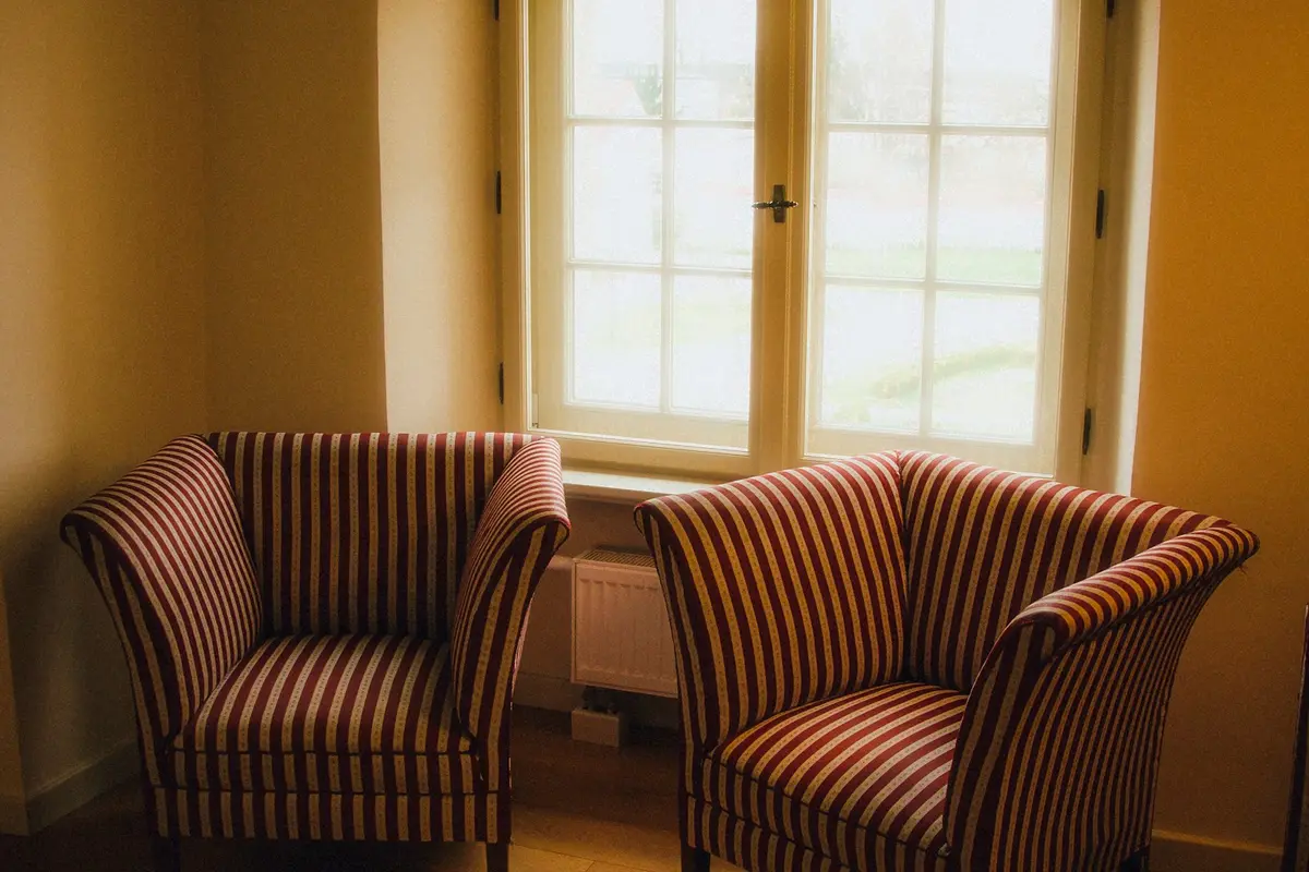 Two armchairs turned toward each other by a sunlit window