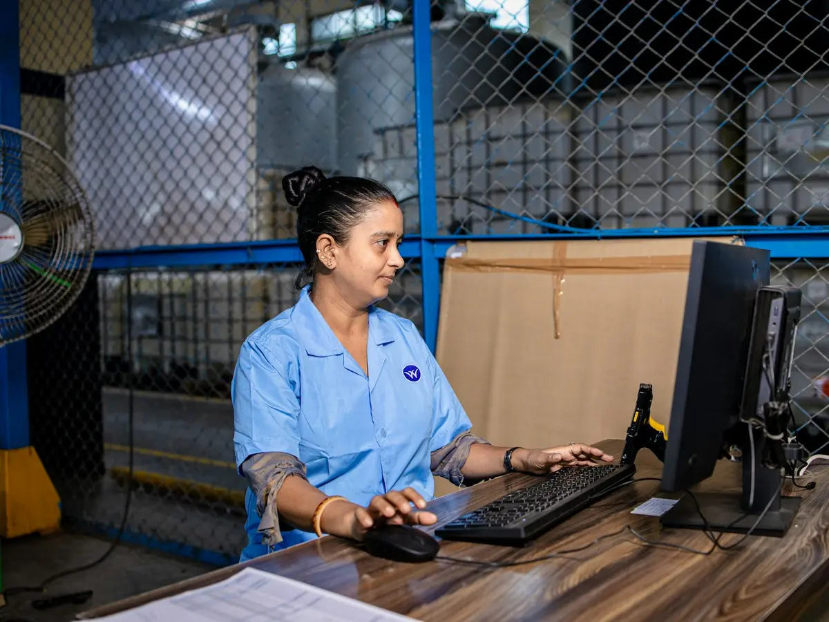 A woman at her workstation in a warehouse office, working on a computer