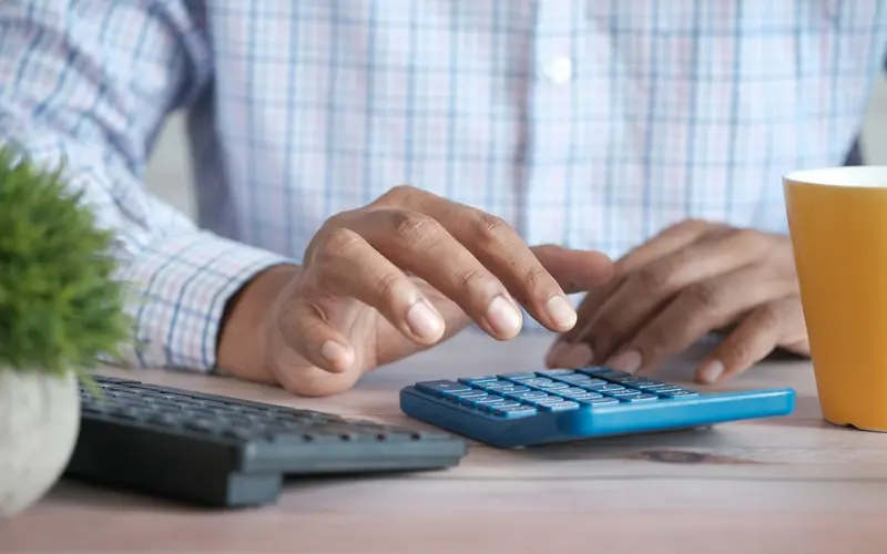 Hands working out figures on a calculator at a desk