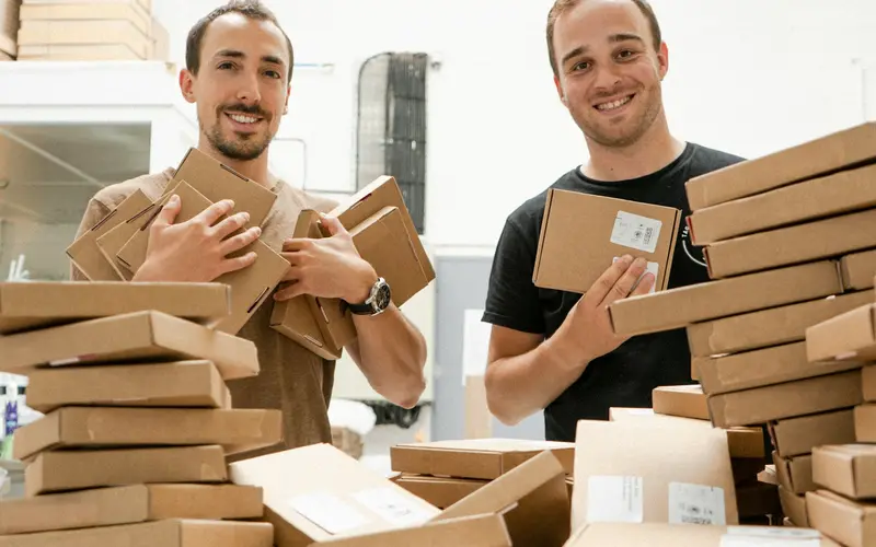 Two people handling a large delivery of parcels